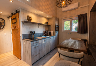 Moderne, kompakt indrettet tiny house med køkken, spisebord og trædetaljer i Vakantiepark De Wiltzangh.
