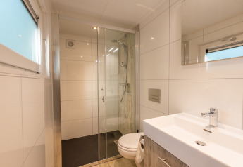 Moderne, kompakt badeværelse med bruseniche, toilet og vask i Tiny Borg på Vakantiepark De Wiltzangh.