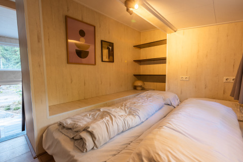 Chambre dans Tiny Borg, Vakantiepark De Wiltzangh, Pays-Bas, lit douillet, étagères et décor moderne.