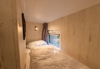 Coin nuit confortable au Tiny Borg, Vakantiepark De Wiltzangh, Pays-Bas, lit près d’une fenêtre.