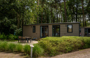 Mobil-home Extra Luxe au Familiepark Goolderheide en Belgique, entouré d’arbres et d’un espace extérieur.