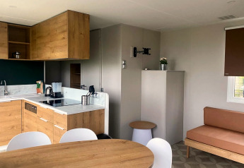 Cucina e soggiorno moderni in casa mobile con arredi in legno in Extra Luxe Stacaravan, Familiepark Goolderheide, Belgio.