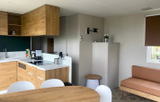 Moderne mobilhome køkken og stue med træmøbler i Extra Luxe Stacaravan, Familiepark Goolderheide, Belgien.