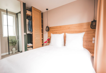 Chambre lumineuse et moderne avec lit double dans une Extra Luxe Stacaravan au Familiepark Goolderheide, Belgique.