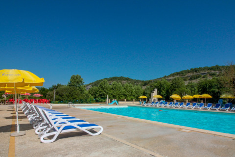 Buitenzwembad met ligstoelen en gele parasols in La Draille, een vakantiepark in Occitanie, Frankrijk.