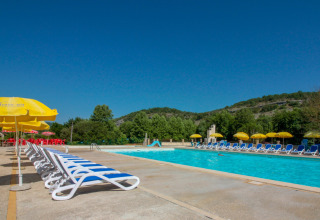 Buitenzwembad met ligstoelen en gele parasols in La Draille, een vakantiepark in Occitanie, Frankrijk.