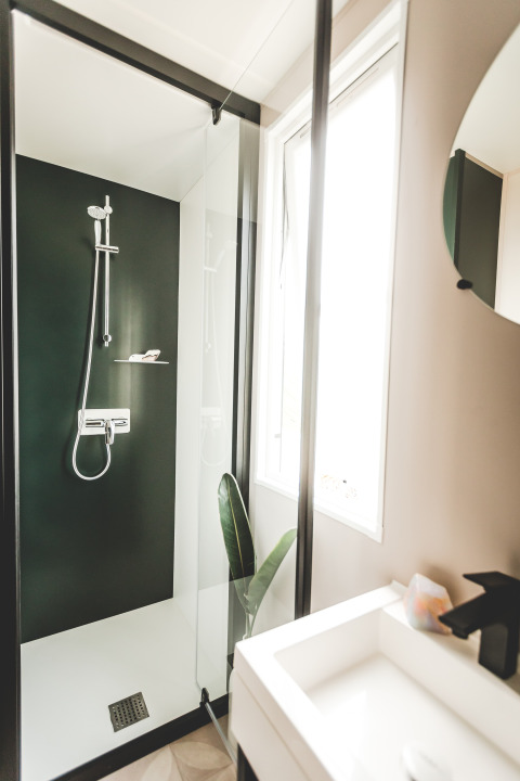 Modern shower in a mobile home at Familiepark Goolderheide, Belgium, featuring green wall and glass door.