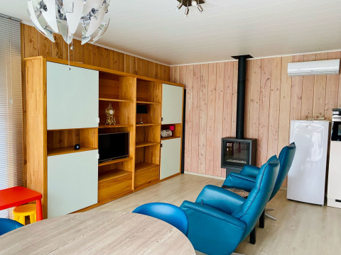 Modern living room inside Chalet at Familiepark Goolderheide, Belgium, featuring blue chairs and a stove.