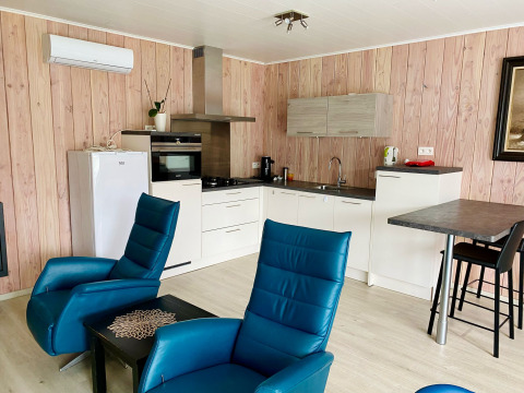 Moderne Küche und Wohnbereich mit blauen Sesseln im Chalet im Family Park Goolderheide, Belgien.