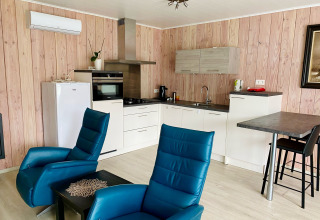 Cuisine et espace salon modernes avec fauteuils bleus dans un chalet du Family park Goolderheide en Belgique.