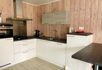 Cocina moderna en Chalet del Familiepark Goolderheide, Bélgica, con paredes de madera y gabinetes blancos.