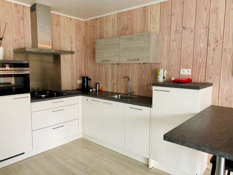 Cuisine moderne dans un Chalet à Familiepark Goolderheide, Belgique, avec murs en bois et meubles blancs.