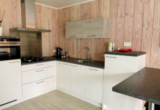 Cocina moderna en Chalet del Familiepark Goolderheide, Bélgica, con paredes de madera y gabinetes blancos.