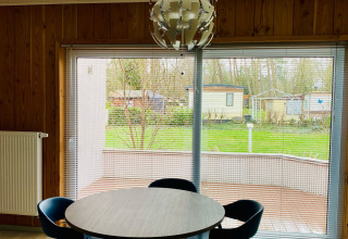 Sala da pranzo moderna nello Chalet al Familiepark Goolderheide, Belgio, con vista sul giardino dalle finestre.