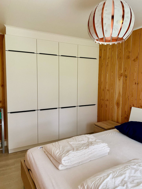 Chambre d’un chalet au Familiepark Goolderheide, Belgique, avec armoire moderne et murs en bois.