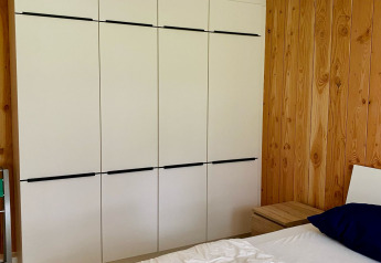 Chambre d’un chalet au Familiepark Goolderheide, Belgique, avec armoire moderne et murs en bois.
