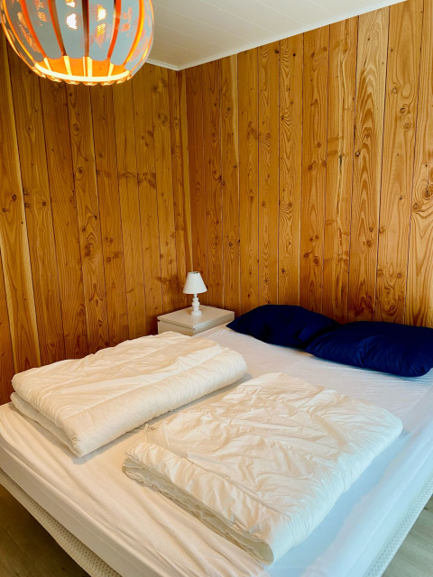 Camera da letto in uno chalet presso Familiepark Goolderheide, Belgio, con pareti in legno e lampada.