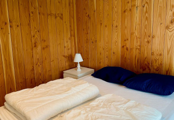 Camera da letto in uno chalet presso Familiepark Goolderheide, Belgio, con pareti in legno e lampada.