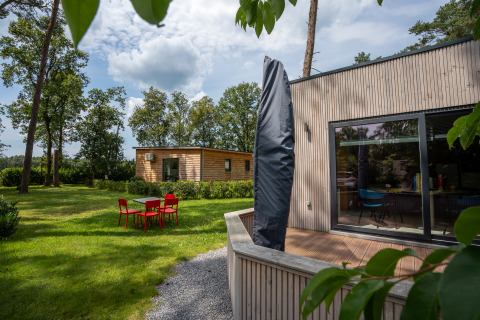 Outdoor photo of Chalet at Familiepark Goolderheide, Belgium, showing garden, patio and red chairs.