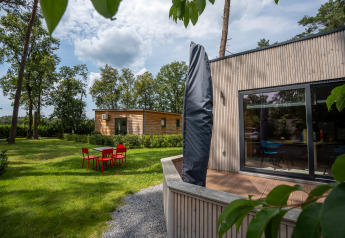 Outdoor photo of Chalet at Familiepark Goolderheide, Belgium, showing garden, patio and red chairs.