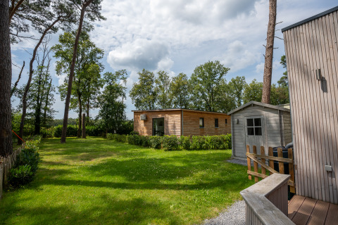 Giardino verde con chalet in legno e capanno a Familiepark Goolderheide in Belgio.