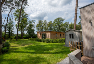 Grüner Garten mit Holzhütte und Schuppen beim Chalet im Familiepark Goolderheide in Belgien.