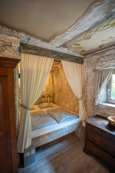 Camera accogliente con letto a tende e decorazione rustica nel Hobbit huisje, Familiepark Goolderheide, Belgio.