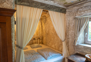 Acogedor dormitorio con cama con cortinas y decoración rústica en Hobbit huisje, Familiepark Goolderheide, Bélgica.