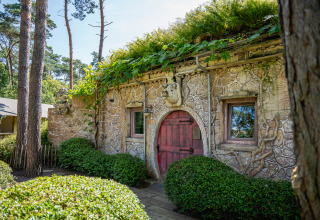 Charming Hobbit house with stone walls, red door, and greenery at Familiepark Goolderheide in Belgium