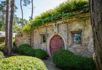 Accogliente casa Hobbit con muri in pietra e porta rossa a Familiepark Goolderheide, Belgio