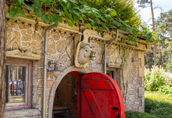 Charmante cabane en pierre avec toit végétalisé et porte rouge au Hobbit huisje, Goolderheide, Belgique.