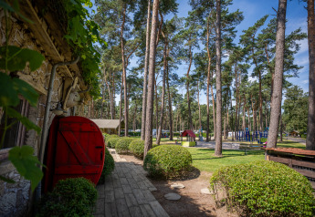 Vue depuis le Hobbit huisje au Familiepark Goolderheide en Belgique, avec pelouse, arbres et aire de jeux.