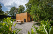 Vista esterna dello Chalet al Familiepark Goolderheide in Belgio, circondato da alberi e tavolo da picnic.
