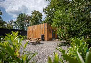 Vista esterna dello Chalet al Familiepark Goolderheide in Belgio, circondato da alberi e tavolo da picnic.