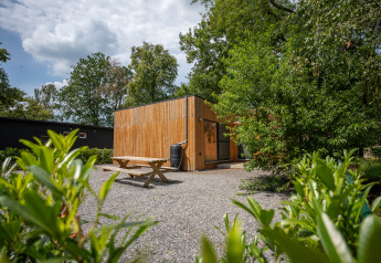 Vista esterna dello Chalet al Familiepark Goolderheide in Belgio, circondato da alberi e tavolo da picnic.