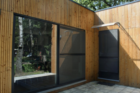 Façade d'un chalet moderne en bois avec de grandes fenêtres à Familiepark Goolderheide en Belgique.