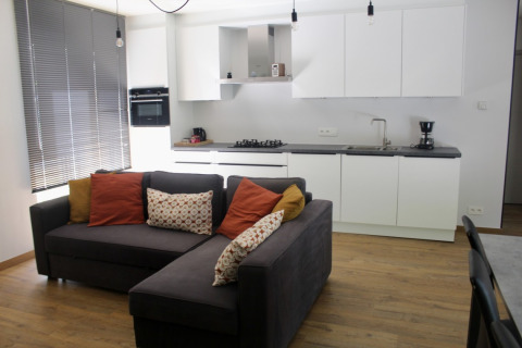 Soggiorno e cucina moderni in Chalet al Familiepark Goolderheide, Belgio, con divano e mobili bianchi.