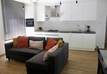 Sala de estar y cocina modernas en Chalet en Familiepark Goolderheide, Bélgica, con sofá y gabinetes blancos.
