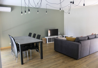 Salon moderne et coin repas au Chalet du Familiepark Goolderheide, Belgique, avec canapé gris et TV.