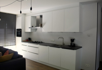 Cocina moderna con gabinetes blancos y encimera negra en Chalet del Familiepark Goolderheide, Bélgica.