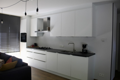 Cucina moderna con mobili bianchi e piano nero nello Chalet presso Familiepark Goolderheide, Belgio.