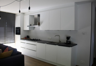 Modern kitchen with white cabinets and black countertop in Chalet at Familiepark Goolderheide, Belgium.