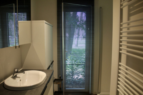 Bagno moderno nello chalet al Familiepark Goolderheide, Belgio, con lavandino, armadio e tende alla finestra.