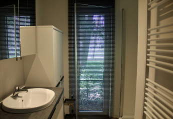 Bagno moderno nello chalet al Familiepark Goolderheide, Belgio, con lavandino, armadio e tende alla finestra.