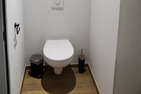 Bagno moderno in uno chalet presso Familiepark Goolderheide, Belgio, con pavimento effetto legno e pareti bianche.