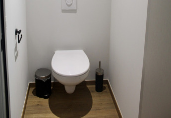 Modernes WC im Chalet im Familiepark Goolderheide, Belgien, mit Holzfußboden und weißen Wänden.