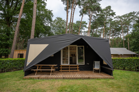 Tienda safari Cooc tent deluxe en Familiepark Goolderheide, Bélgica, con porche de madera y entorno boscoso.