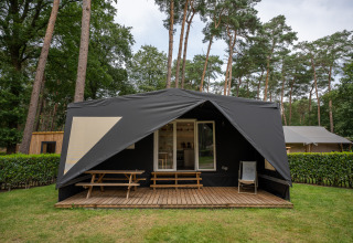Tienda safari Cooc tent deluxe en Familiepark Goolderheide, Bélgica, con porche de madera y entorno boscoso.