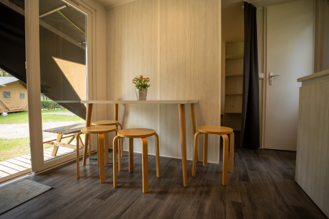 Interior de la tienda Cooc tent deluxe en Familiepark Goolderheide, Bélgica, con mesa y taburetes.