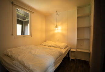 Camera da letto nella Cooc Tent Deluxe di Familiepark Goolderheide, Belgio, con letto matrimoniale e luce calda.